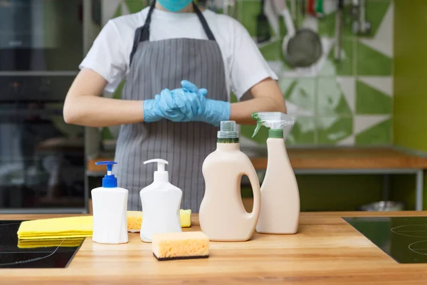 Woman showing eco disinfection detergents for cleaning kitchen surfaces