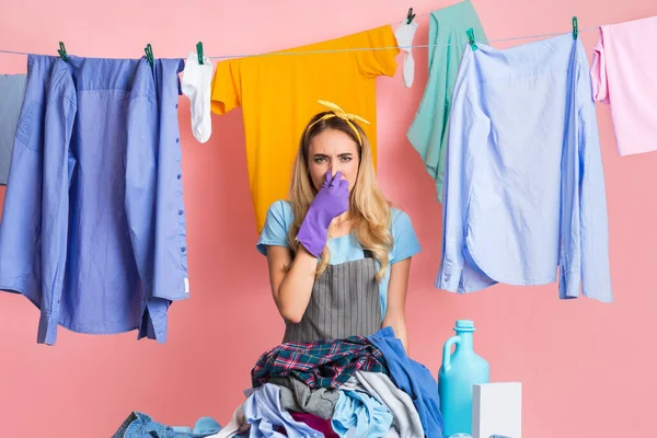 Dona de casa fecha o nariz na frente de montão de roupas sujas — Fotografia de Stock