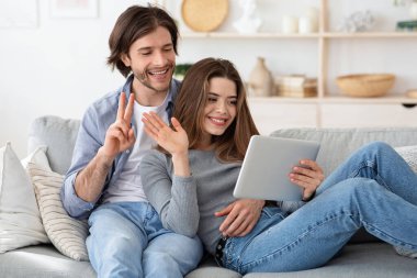 Kadın ve erkek video konferansı yapıyor, evde tablet kullanıyorlar.