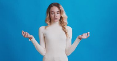 Genç bir kadın, gözleri kapalı meditasyon yapıyor ve parmaklarını Mudra jestinde tutuyor.