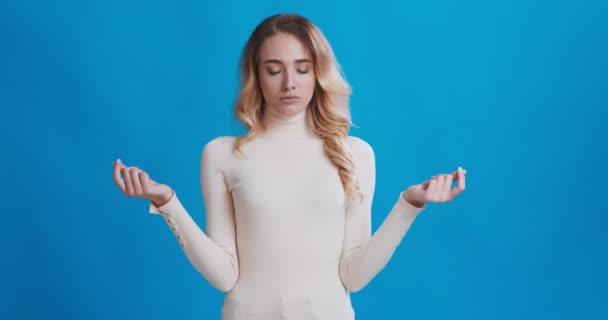 Genç bir kadın, gözleri kapalı meditasyon yapıyor ve parmaklarını Mudra jestinde tutuyor. — Stok video