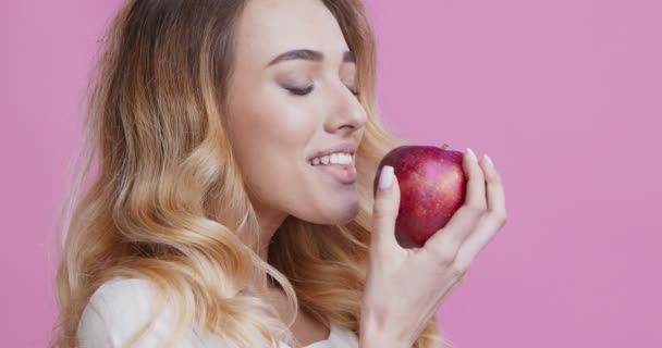 Chica mordiendo manzana roja y ampliamente sonriente, primer plano retrato — Vídeos de Stock