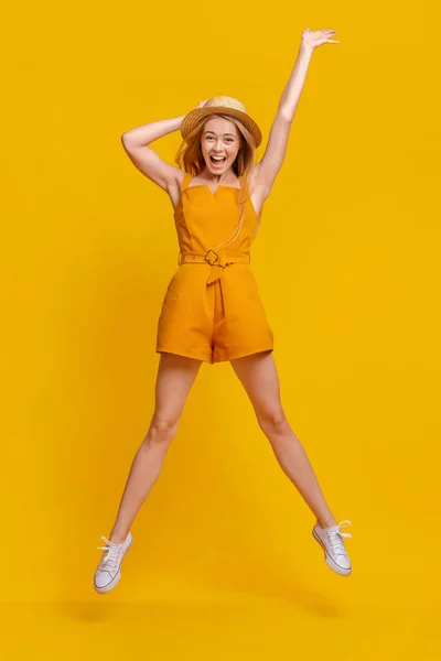 Zomer plezier. Joyful jong meisje in jumpsuit en hoed springen in de lucht — Stockfoto