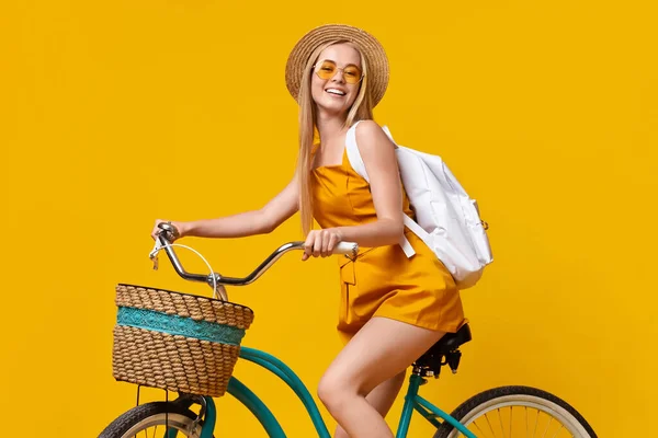 Yaz stili. Şapkalı, güneş gözlüklü ve bisiklet süren genç bir kız. — Stok fotoğraf