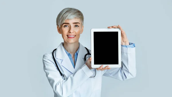 Gülen kadın doktor tableti boş ekranla gösteriyor — Stok fotoğraf