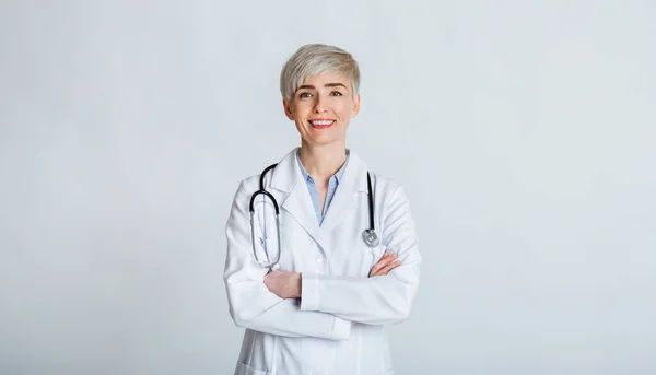 Concepto médico amigable. Mujer de abrigo blanco con brazos cruzados y estetoscopio —  Fotos de Stock