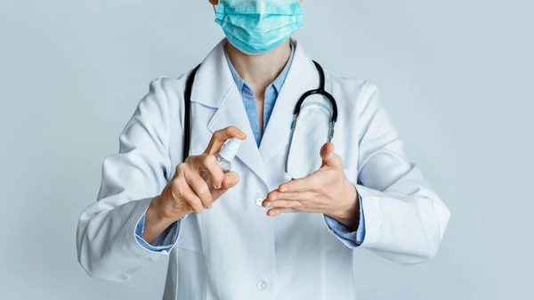 Il concetto di disinfezione. Medico in maschera protettiva strofina le mani con antisettico — Foto Stock