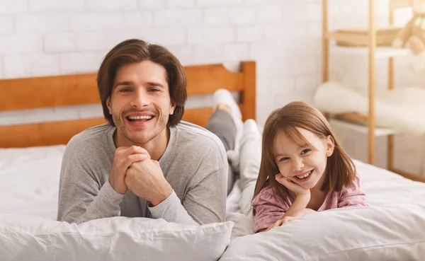 Alegre papai e seu liitle menina deitado no cama, sorrindo — Fotografia de Stock