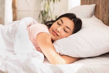 Asian Woman Sleeping Lying In Bed At Home Hugging Pillow clipart