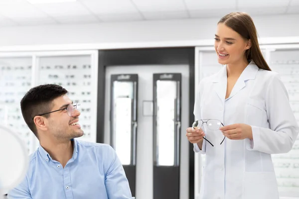 Optometrista ayudando al hombre a elegir gafas de corrección —  Fotos de Stock