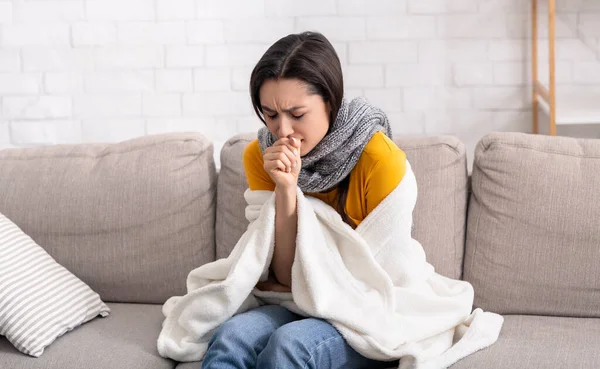Sick young lady suffering from virus, coughing into her hand at home — Stock Photo, Image