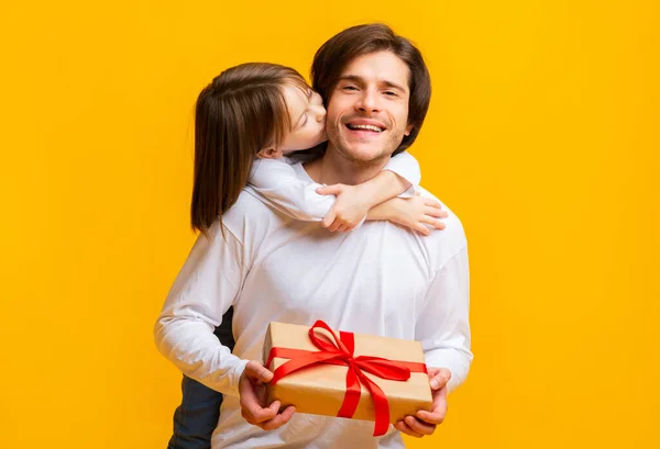 Piccola figlia baciare compleanno padre su sfondo giallo — Foto Stock