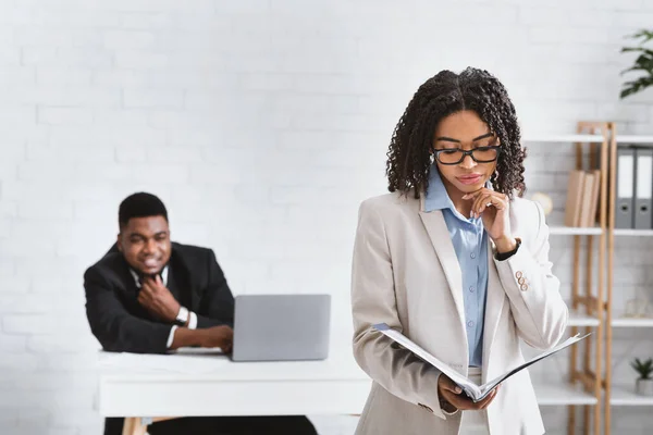 Szexuális zaklatás. Fiatal afro-amerikai üzletember bámulja női munkatársát az irodában — Stock Fotó