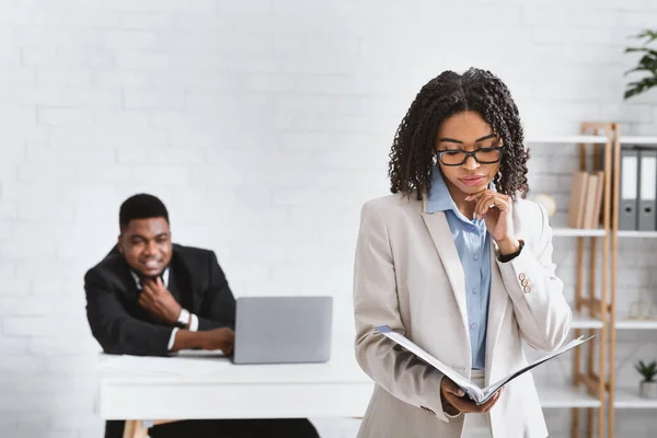 Abuso sexual. Joven hombre de negocios afroamericano mirando a su compañera de trabajo en la oficina — Foto de Stock