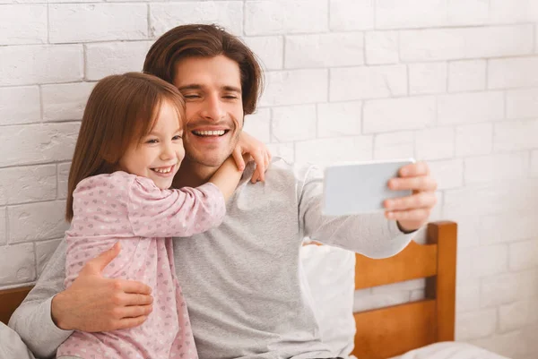 Positivo pai e filha tomando selfie no quarto — Fotografia de Stock