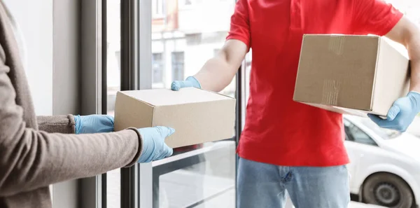 Conceito de entrega em domicílio. Courier em luvas de borracha dá caixa ao cliente na porta — Fotografia de Stock