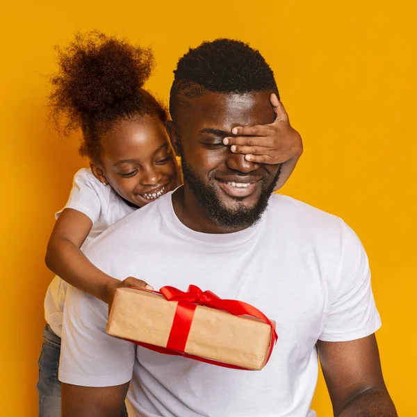 Alegre poco afro hija cerrando papá ojos y dando regalo caja — Foto de Stock