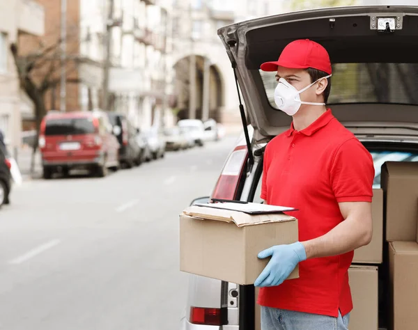 Perlindungan klien dari coronavirus setelah pengiriman paket ke rumah. Kurir dekat bagasi mobil yang terbuka. — Stok Foto