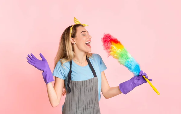 Счастливая домохозяйка в фартуке и резиновых перчатках, поющая разноцветной кистью — стоковое фото