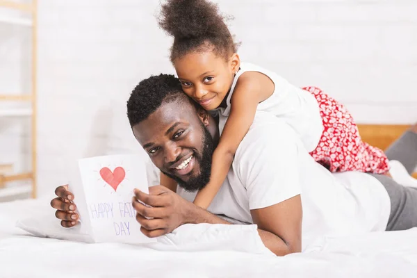 Petite fille félicitant son papa avec Fathers Day avec carte de vœux — Photo