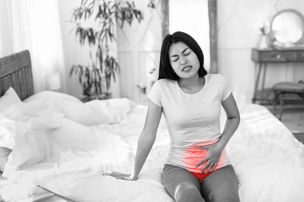 Asian Woman Suffering From Lower Abdomen Pain At Home, Black-And-White — Stock Photo, Image