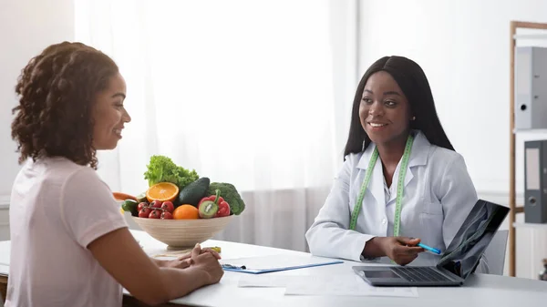 Dietista consulenza giovane signora in clinica, utilizzando il computer portatile — Foto Stock