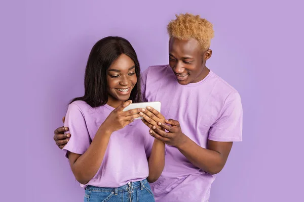 Joyful menina afro-americana e cara conversando no telefone celular juntos, fundo violeta — Fotografia de Stock