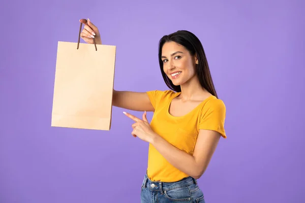 Snygg kvinna pekar på papper shoppingväska — Stockfoto