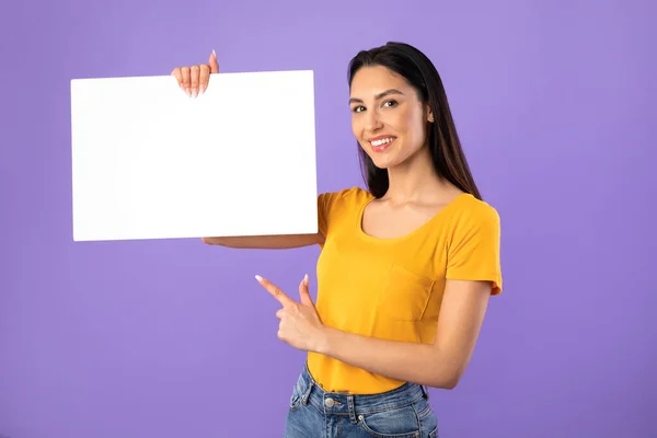 Heureuse jeune fille pointant vers le papier blanc — Photo
