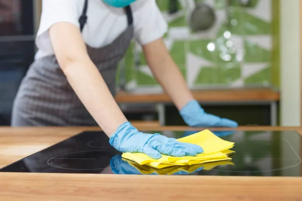Jeune femme méconnaissable désinfectant comptoir de cuisine avec microfibre — Photo