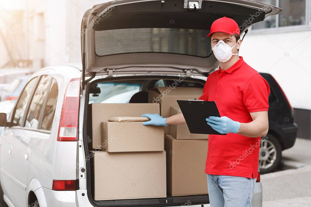 Delivery man is checking parcel. Courier with tablet, put his hand on box in car