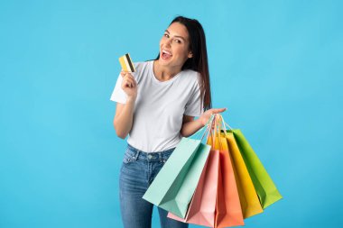 Alışveriş torbaları ve plastik kartlarla neşeli bir kadın.