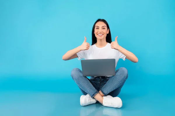 Happy teenager sitting with laptop showing thumbs up — Stock Photo, Image