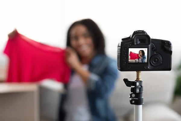 Câmera de gravação jovem preto mulher unboxing pacote com novas roupas em casa — Fotografia de Stock