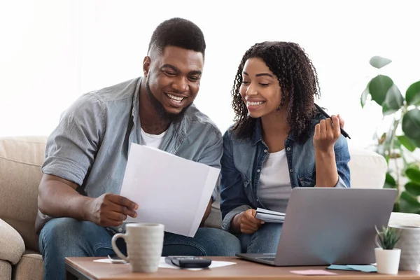 Μαύρο ζευγάρι διαβάζει οικονομικά έγγραφα στο σπίτι ενώ σχεδιάζει οικογενειακό προϋπολογισμό — Φωτογραφία Αρχείου