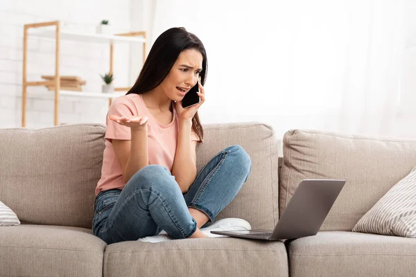 Donna frustrata che parla sul cellulare seduta sul divano — Foto Stock