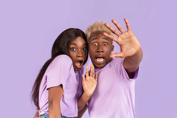 Retrato de pareja negra con caras asustadas o conmocionadas sobre fondo lila — Foto de Stock