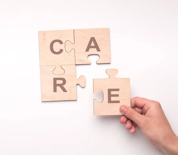 Close-up van een vrouw die een houten puzzel samenstelt met het woord CARE, geïsoleerd op wit. Collage — Stockfoto