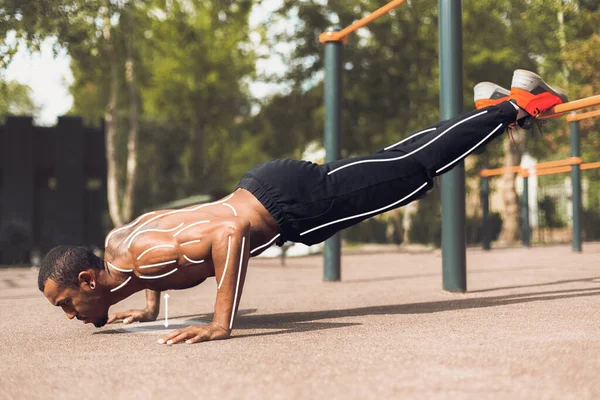 Exercício de força ao ar livre. Atraente homem afro-americano fazendo flexões em campo de esportes, colagem — Fotografia de Stock