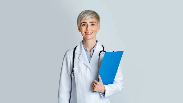 Bezoek aan doktersconcert. Vriendelijke vrouwelijke arts in witte vacht en tabletten in de hand — Stockfoto