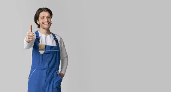 Lächelnder Handwerker mit Pinsel in der Tasche, Daumen hoch, heller Hintergrund — Stockfoto