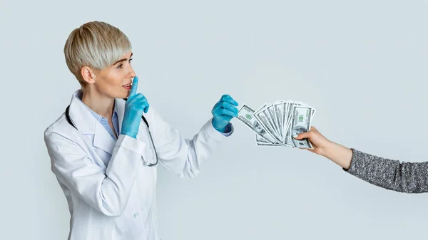 Woman doctor in medical gloves takes money from patient hands and makes sign of silence — Stock Photo, Image
