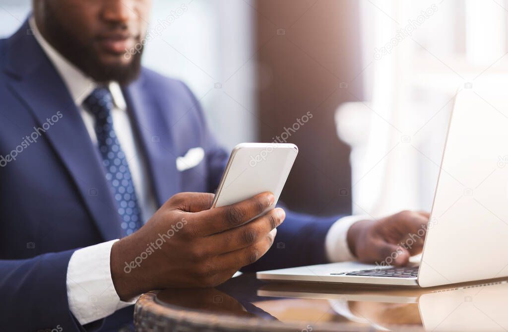 Unrecognizable African Entrepreneur Using Cellphone Working In Cafe In City