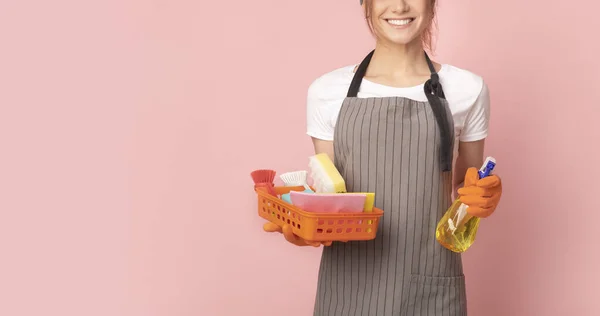 Serviços de limpeza doméstica. Empregada doméstica sorridente em avental com suprimentos domésticos em mãos — Fotografia de Stock