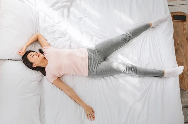 Chino chica durmiendo acostado en divertido pose en cama en interior —  Fotos de Stock