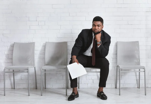 Joven negro sintiéndose agotado por esperar su entrevista de trabajo en el salón de oficinas. Espacio vacío — Foto de Stock