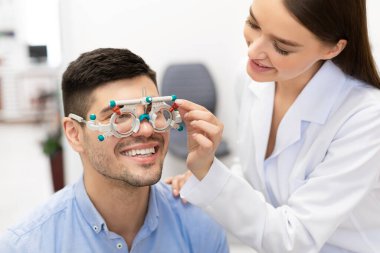 Optometrist klinikte hasta vizyonunu deneme çerçevesi ile kontrol ediyor