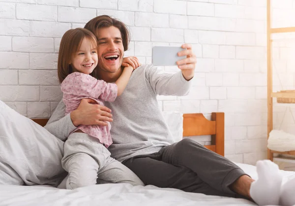 Menina pré-escolar feliz e pai tomando selfie no smartphone — Fotografia de Stock