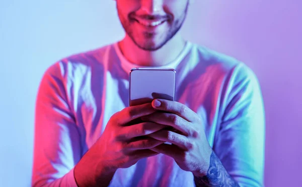 Millennial man is online. Glimlachende man typt in smartphone — Stockfoto