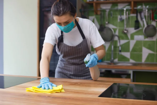 Wanita bertopeng pelindung dan sarung tangan membersihkan dapur — Stok Foto